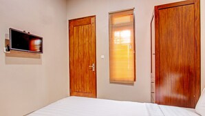 A bedroom with a bed, wooden doors, a window with blinds, and a mounted television. - OYO Life 93497 Griya Kost Rr (Salatiga)
