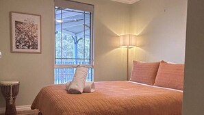 Une chambre à coucher avec un lit, un ventilateur de plafond, une fenêtre donnant sur un beau paysage, une lampe et une batterie de percussion.