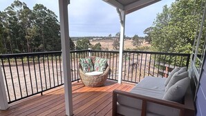 A wooden deck with a wicker chair and a bed with pillows. - Belmira Vines
 Private Vineyard Escape! (Kangaroo Gully)
