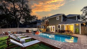 A backyard with a swimming pool, lounge chairs, and a wooden deck.