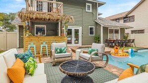A backyard with a pool, outdoor seating, and a bar area.