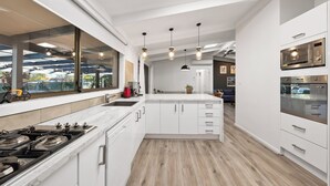 Une cuisine moderne avec des meubles blancs, un grand îlot central et des appareils électroménagers en acier inoxydable.