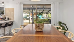 Un espace repas moderne avec une table en bois, un centre de table composé d’un panier tressé et des tabourets de bar.
