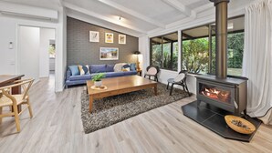 Un salon moderne avec une cheminée, un canapé, une table basse et un coin repas.