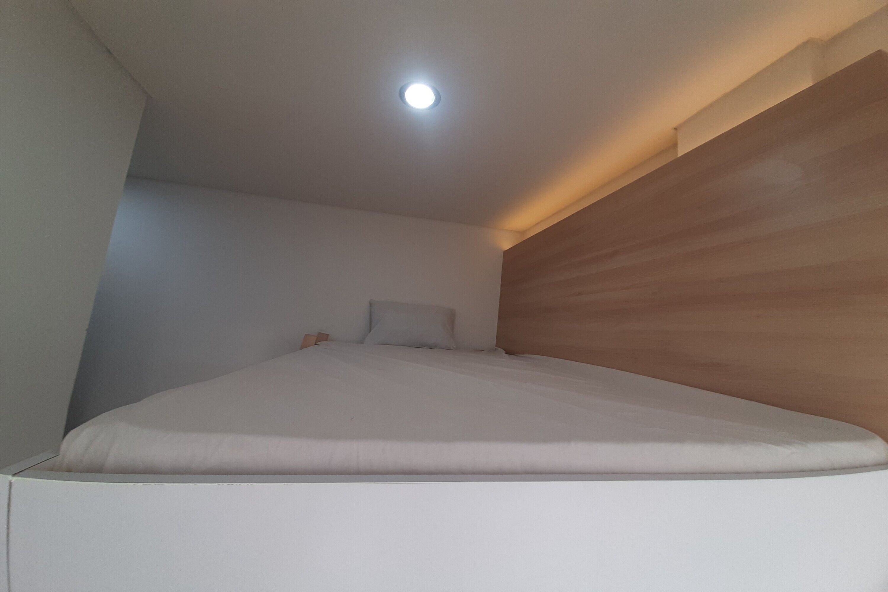 A bedroom with a bed, a ceiling light, and a wooden wall.