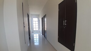 Un pasillo con puertas a ambos lados que conduce a una habitación luminosa con un gran ventanal.