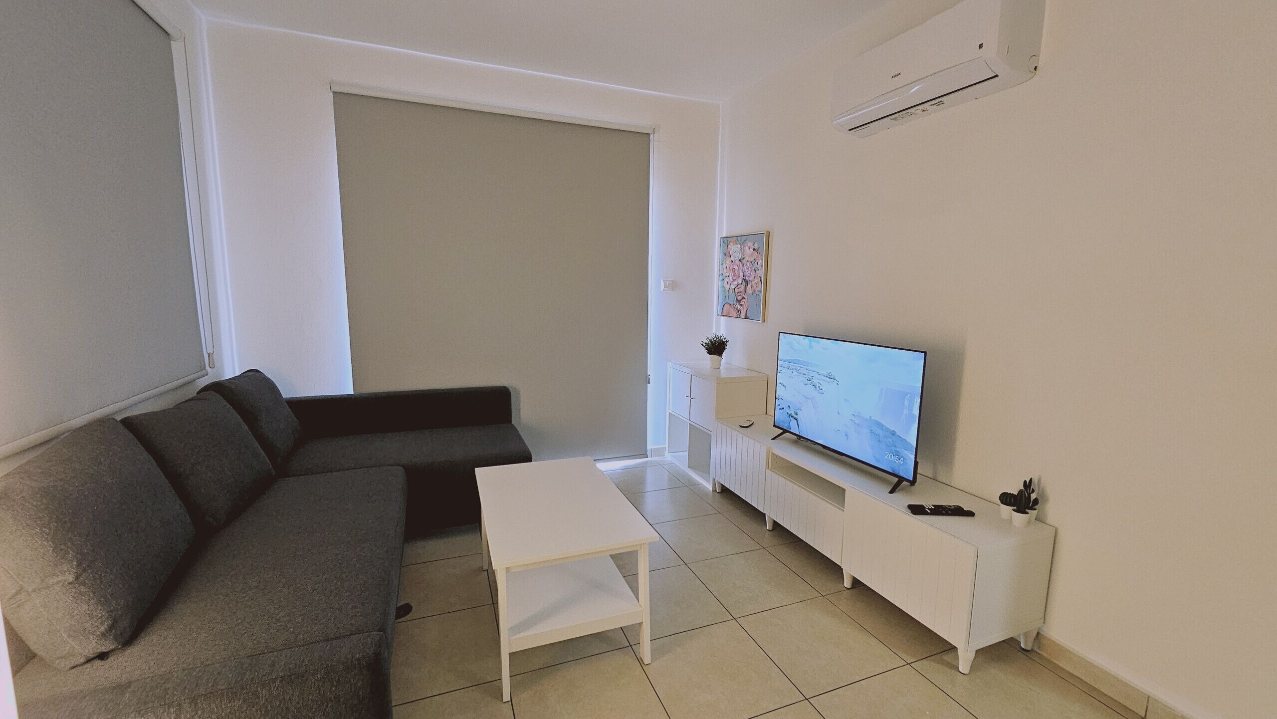 Un salon avec un canapé, une table basse, un téléviseur posé sur un meuble et un buffet.