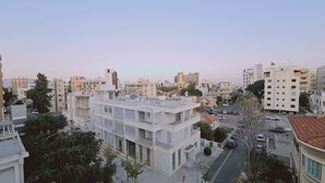 A multi-story building with balconies, a parking area, and a street view. - STAY Cosmo City Suite 303 (Nicosia)