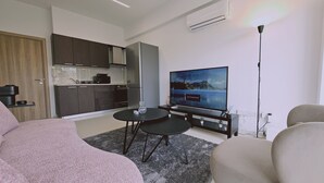A modern living room with a flat-screen TV, a dining area, and a kitchen. - STAY Cosmo City Suite 102 (Nicosia)