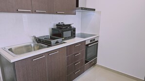 A kitchen with a stainless steel sink, a microwave, a toaster, and a built-in oven. - STAY Cosmo City Suite 302 (Nicosia)