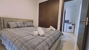 A bedroom with a bed, a wardrobe, and a washing machine. - STAY Cosmo City Suite 302 (Nicosia)