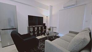 A modern living room with a flat-screen TV, a black sofa, a grey sofa, and a coffee table. - STAY Cosmo City Suite 302 (Nicosia)