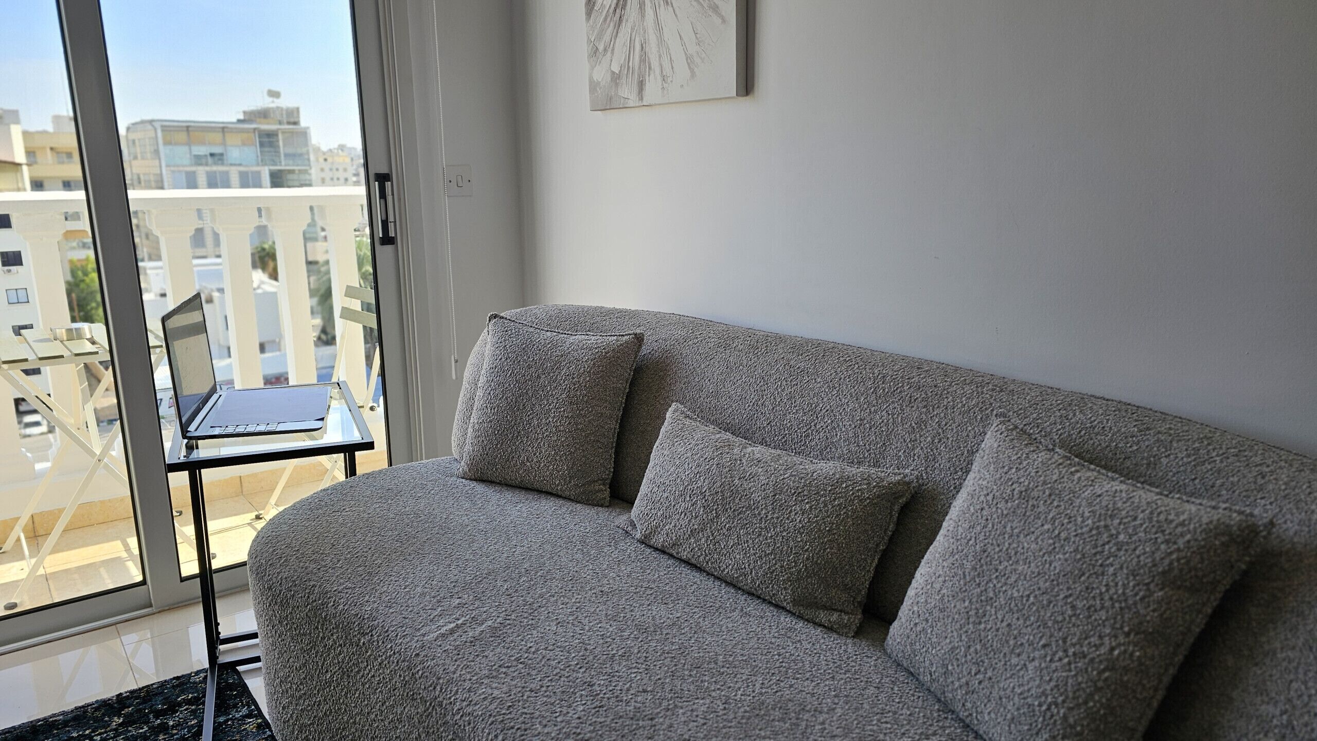 Ein graues Sofa mit zwei Kissen in einem Zimmer mit einem großen Fenster.