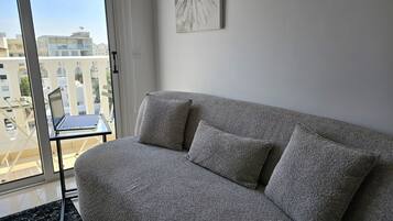 Ein graues Sofa mit zwei Kissen in einem Zimmer mit einem großen Fenster.