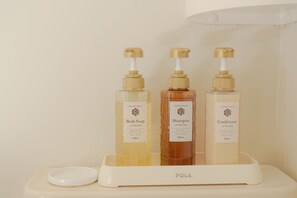Tres botellas de productos de baño sobre una bandeja blanca.