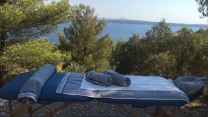 Una sdraio con asciugamani, con vista su un lago, alberi e colline sullo sfondo.