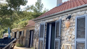Un edificio in pietra con tetto in tegole, persiane di legno e una panchina di legno.