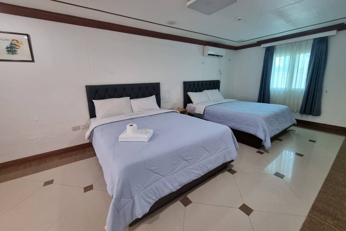 A hotel room with two beds, a large mirror, and a picture on the wall.