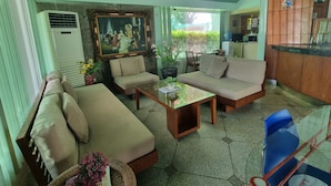 En stue med en beige sofa, et glasbord og et billede på væggen.