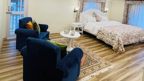 A hotel room with a bed, a sofa, a small table, and a window. - Upani Cottages (Srinagar)
