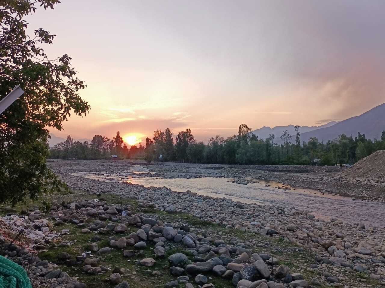 A river with rocks and trees during sunset.