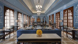 A grand room with a chandelier, blue walls, and a central table with a vase of flowers.