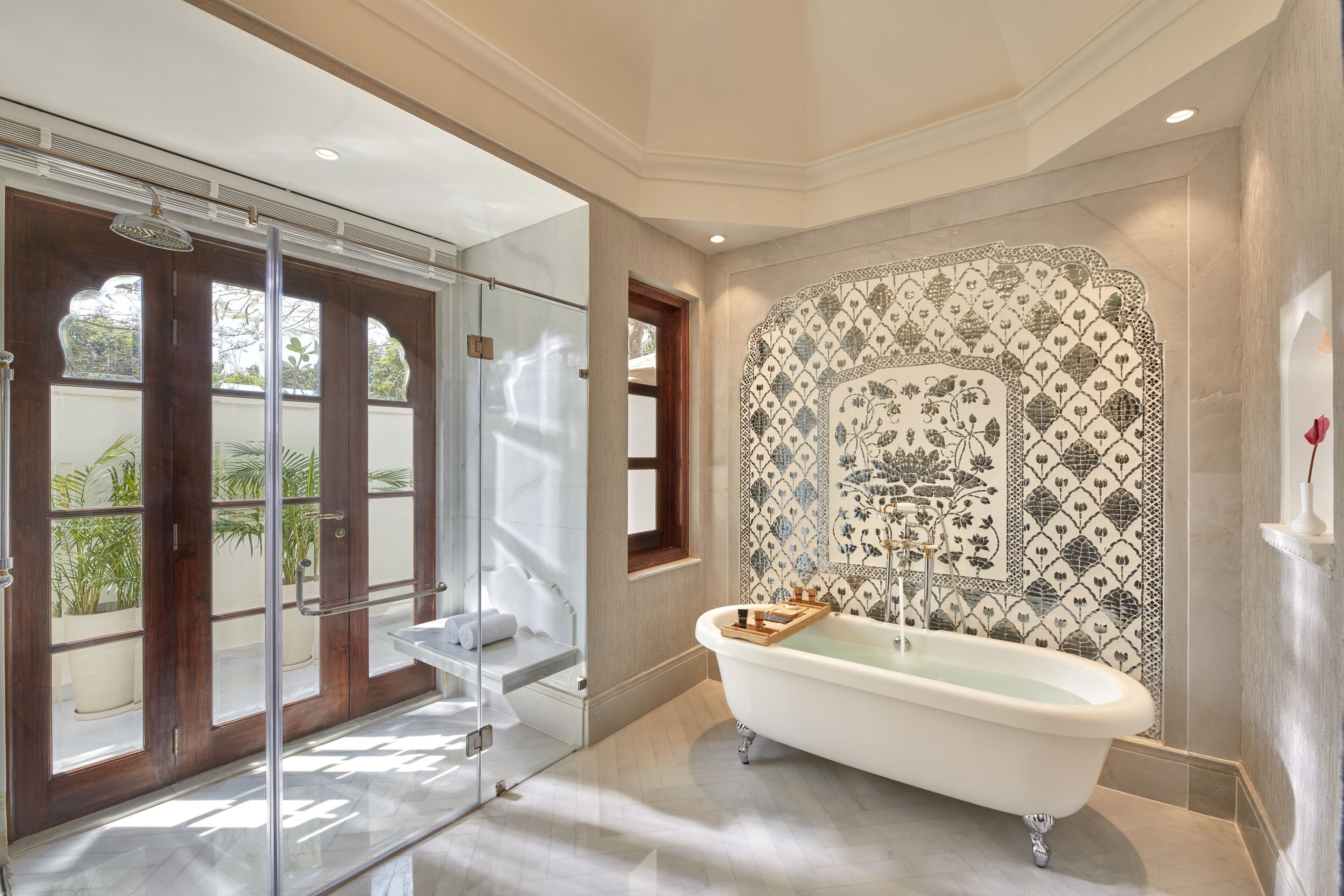 A bathroom with a freestanding bathtub, a glass shower enclosure, and a decorative tiled wall.