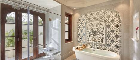 A bathroom with a freestanding bathtub, a glass shower enclosure, and a decorative tiled wall.