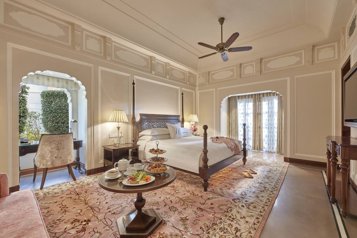 Una habitación de hotel con una cama grande, una mesa redonda con desayuno, un escritorio y una silla.
