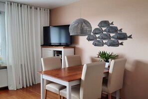 Relax in this stylish living room with a flat-screen TV, dining table, and comfortable seating for four.