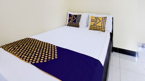 A neatly made bed with a blue and yellow polka dot bedspread and matching pillows. - OYO Life 93257 Kos Anugerah (Mataram)