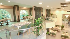 A multi-level restaurant with round tables, glass railings, and potted plants. - paradise home city stars (Cairo)