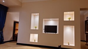 A living room with a flat-screen TV mounted on the wall, surrounded by recessed shelves with small vases. - paradise home city stars (Cairo)