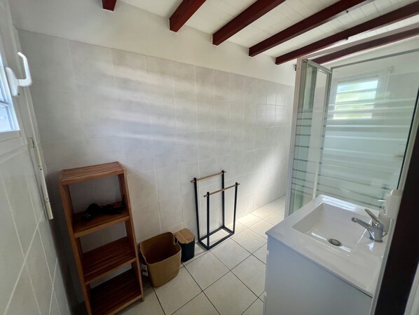 A bathroom with a white sink, wooden shelves, and a tiled floor. - Villa Siméon Saint François (Saint-François)
