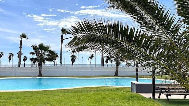 A swimming pool with palm trees and a clear sky. - Apartment in Roquetas near the Beach (Roquetas de Mar)