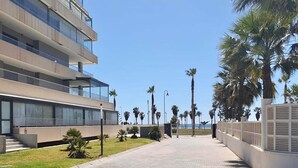 A modern building with multiple balconies, a paved walkway, and palm trees. - Apartment in Roquetas near the Beach (Roquetas de Mar)