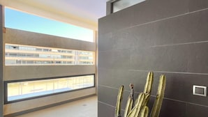 A modern interior with a balcony overlooking a building, grey tiled walls, and a cactus plant. - Apartment in Roquetas near the Beach (Roquetas de Mar)