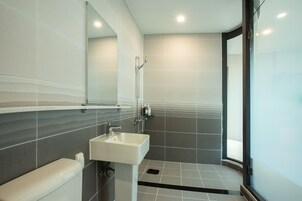 A modern bathroom with a white sink, a glass shower enclosure, and a large mirror.