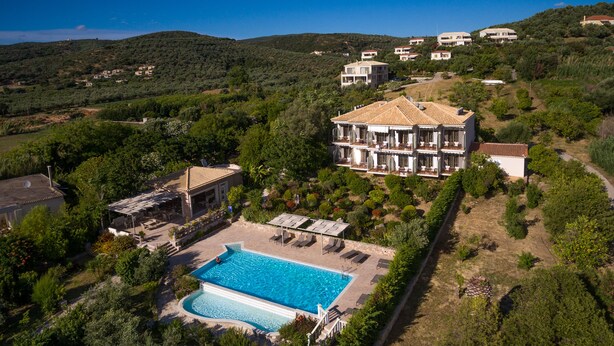 Una amplia villa con piscina, rodeada de exuberante vegetación y otras villas en una ladera.