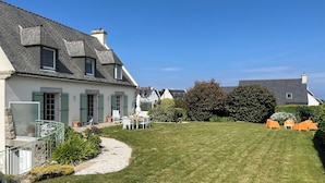 Ein Haus mit gepflegtem Rasen, Außenbereich zum Sitzen und blauem Himmel.