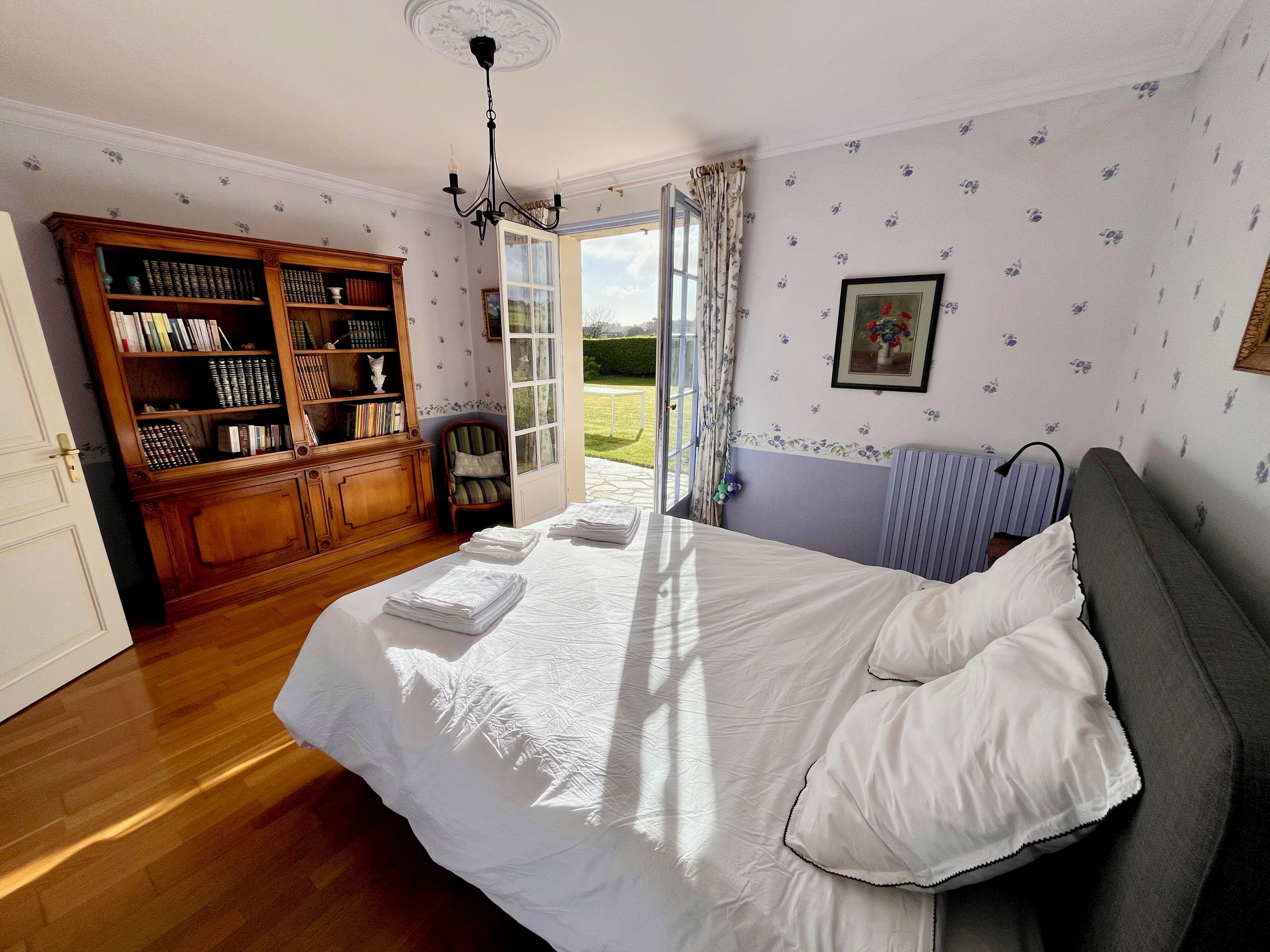 Ein Schlafzimmer mit Bett, Bücherregal, Fenster und Heizkörper.