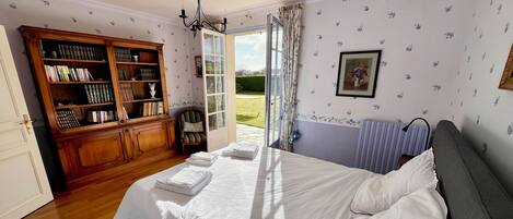 Ein Schlafzimmer mit Bett, Bücherregal, Fenster und Heizkörper.