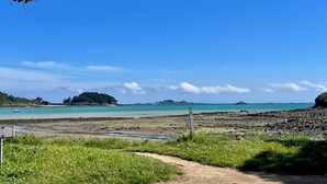 Eine Küstenlandschaft mit klarem Himmel, einem Sandstrand und einem kleinen Boot im Wasser.