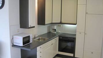 Een koelkast, een magnetron, een koffiezetapparaat/waterkoker, eettafels