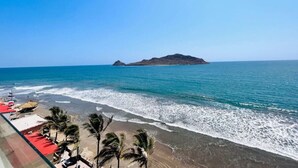 Una playa con vista al océano y una pequeña isla a lo lejos.