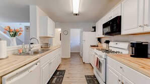 Une cuisine moderne avec des armoires blanches, un évier en acier inoxydable, une cuisinière et un four à micro-ondes.