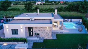 A modern house with a swimming pool, a patio, and a well-maintained lawn. - Villa Rose ZadarVillas (Nin)