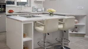 A modern kitchen with a central island, bar stools, a built-in oven, and pendant lighting. - Villa Rose ZadarVillas (Nin)