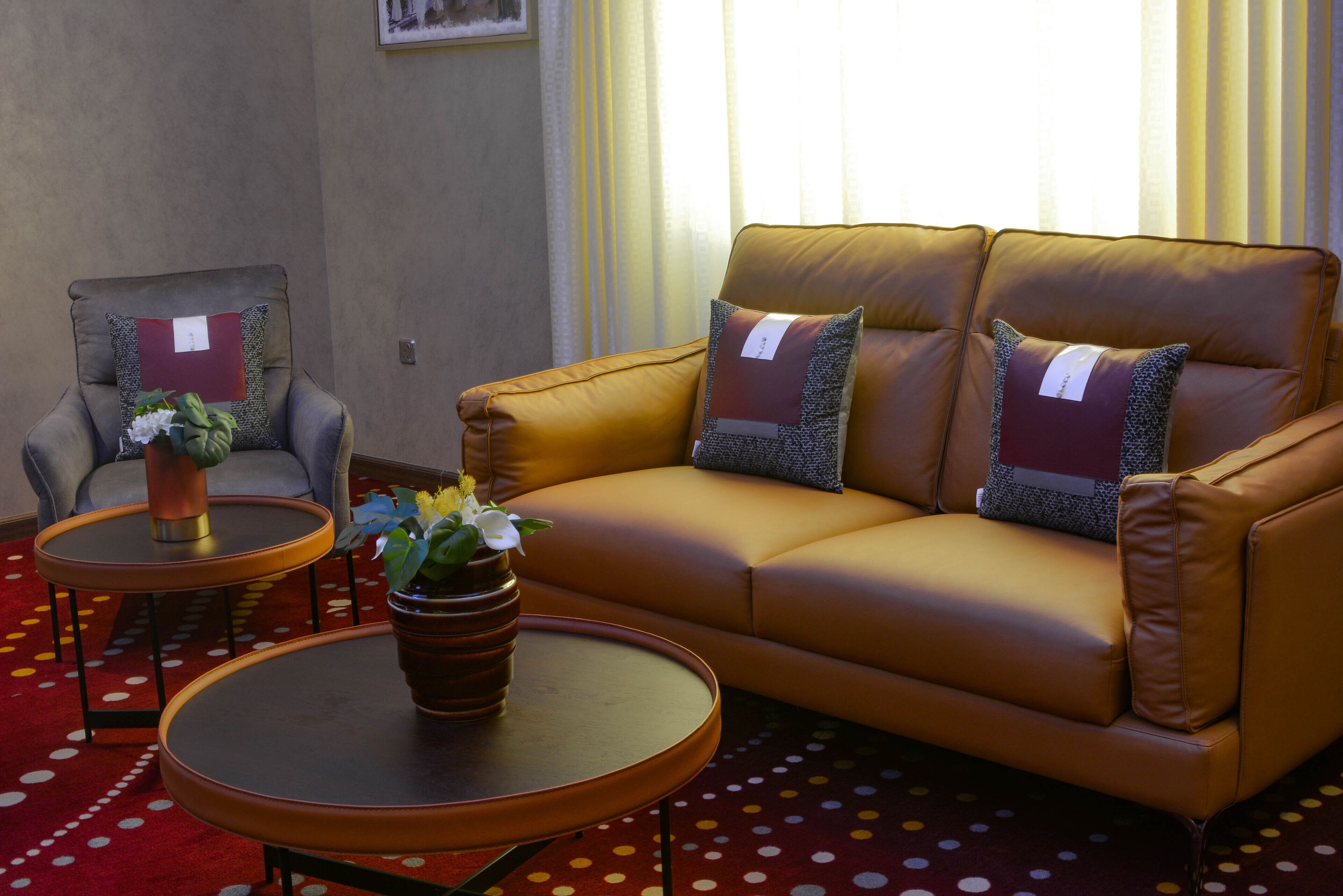 A living room with a brown leather sofa, two armchairs, a coffee table, and a small side table with a potted plant.