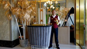 A hotel reception area with a large potted plant, a reception desk, and a modern chandelier. - Redwaves Hotel (Jeddah)